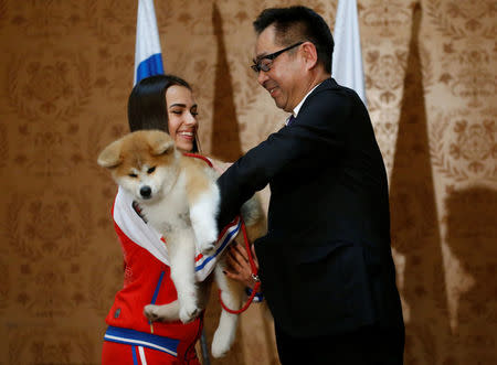 Endo Takashi, head of the Association for the preservation of the purity of the Akito breed, presents an Akita Inu puppy to Russian figure skating gold medallist Alina Zagitova in Moscow, Russia May 26, 2018. REUTERS/Maxim Shemetov