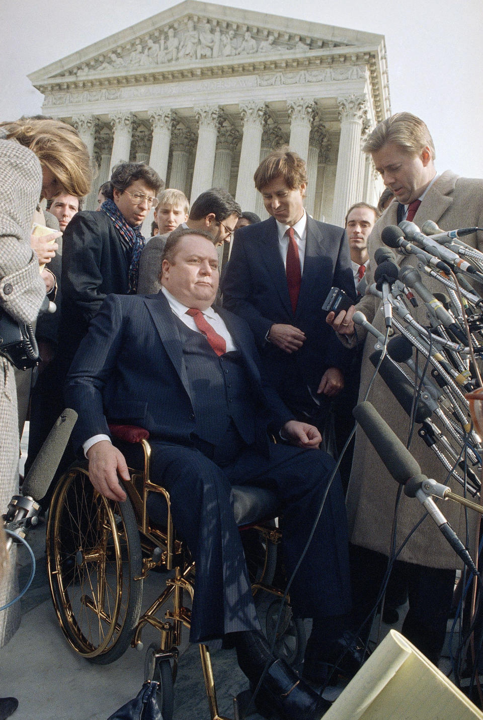 FILE - "Hustler" magazine publisher Larry Flynt leave the Supreme Court building in Washington on Dec. 3, 1987, after a case was heard. Flynt, who turned "Hustler" magazine into an adult entertainment empire while championing First Amendment rights, has died at age 78. His nephew, Jimmy Flynt Jr., told The Associated Press that Flynt died Wednesday, Feb. 10, 2021, of heart failure at his Hollywood Hills home in Los Angeles. (AP Photo/Charles Tasnadi, File)