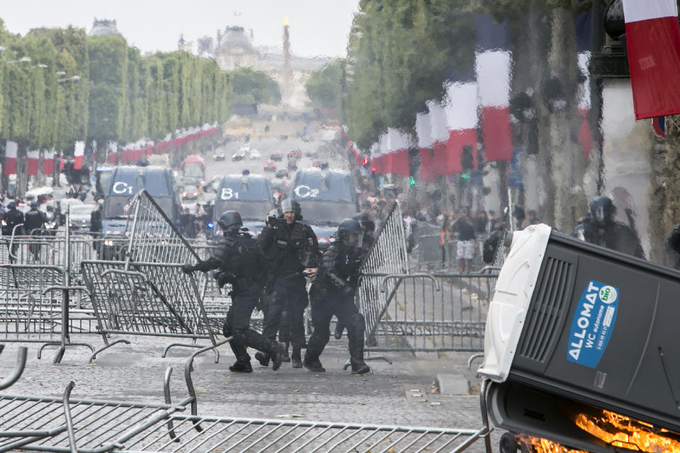 Riot police officers remove barricades that were uses as security barriers for Bastille Day parade on the Champs-Elysees avenue after scuffles with demonstrators, Sunday, July 14, 2019 in Paris. (AP Photo/Rafael Yaghobzadeh)