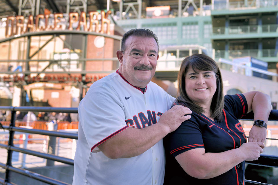 Dan and Tiffany Fuentes, a family that hosted minor league player Tristan Beck, pose for a photo outside Oracle Park before a baseball game between the San Francisco Giants and the New York Mets on Thursday, April 20, 2023, in San Francisco. Giants pitcher Tristan Beck was called up to play his first major league baseball game on April 20. Host family programs were suspended during the coronavirus pandemic over health concerns. When minor league players reached a historic initial collective bargaining agreement with Major League Baseball in March, the league agreed to double salaries and provide guaranteed housing to most players. The use of host families was officially outlawed. (AP Photo/Tony Avelar)