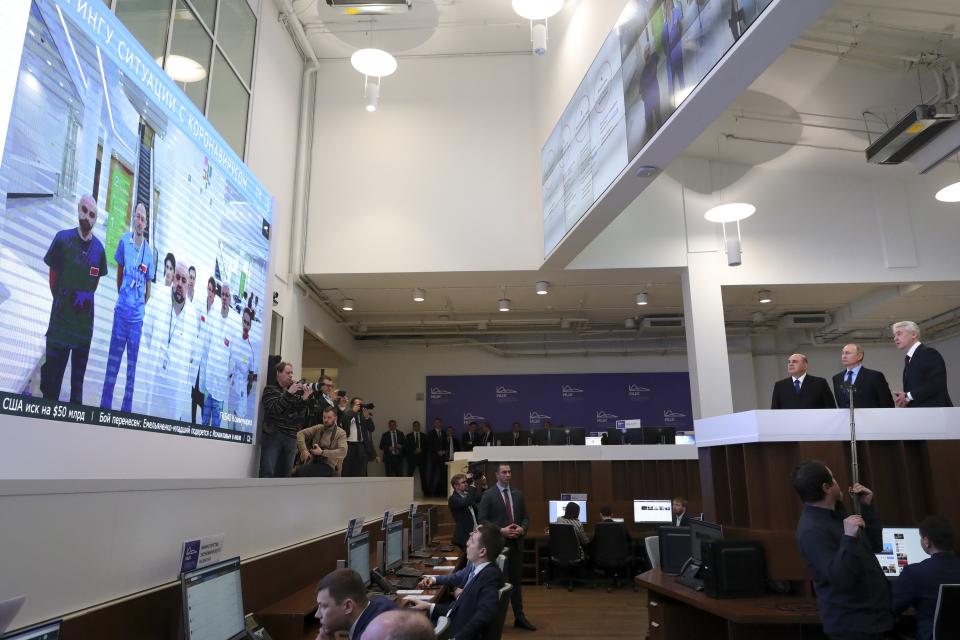 In this photo taken on Tuesday, March 17, 2020, Russian President Vladimir Putin, second right, Prime Minister Mikhail Mishustin, third right, and Moscow Mayor Sergei Sobyanin, right, visit a call center of the emergency response center on control and monitoring of the coronavirus disease, in Moscow, Russia. Russian authorities declared a war on "fake news" related to the new coronavirus. The crusade was triggered by what looked like a real disinformation campaign, but as the outbreak in Russia picked up speed and criticism of the Kremlin's "it is under control" stance mounted, the authorities cracked down on social media users doubting the official numbers and news outlets questioning the government's response to the epidemic. (Mikhail Klimentyev, Sputnik, Kremlin Pool Photo via AP)