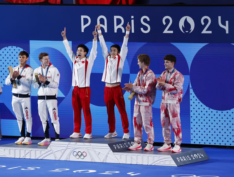 Juegos Olímpicos de París 2024 - Clavados - Plataforma de 10 metros sincronizada masculina Ceremonia de victoria - Centro Acuático, Saint-Denis, Francia - 29 de julio de 2024. Los medallistas de oro Junjie Lian de China y Hao Yang de China reaccionan en el podio con los medallistas de plata Thomas Daley y Noah Williams de Reino Unido y los medallistas de bronce Rylan Wiens y Nathan Zsombor-Murray de Canadá