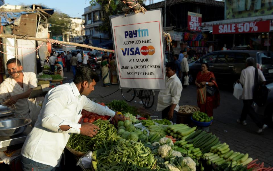 A sign advertising Indian electronic and cellpohne-based payment system PAYTM hangs at a roadside vegetable stall in Mumbai on February 25, 2017.  / AFP / PUNIT PARANJPE        (Photo credit should read PUNIT PARANJPE/AFP/Getty Images)