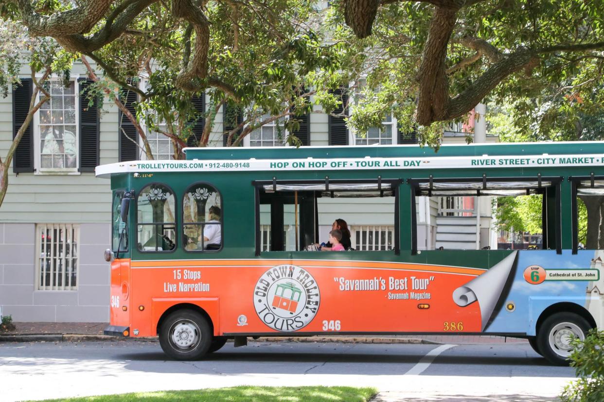 An Old Town Trolley rides around Columbia Square with only 1 family on board.