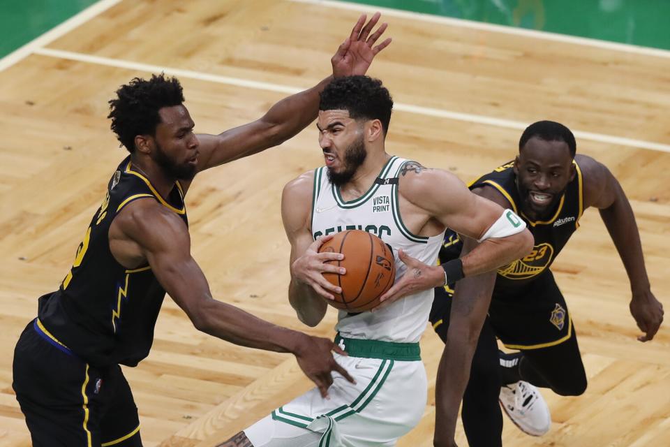 Celtics forward Jayson Tatum tries to split the defense of Warriors forward Andrew Wiggins, left, and Draymond Green.
