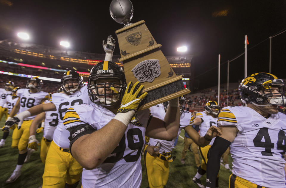 FILE - Iowa defensive lineman Nathan Bazata (99) carries the Heroes Game trophy on the field after an NCAA college football game against Nebraska in Lincoln, Neb., Friday, Nov. 24, 2017. Iowa has regularly recruited football players out of Nebraska, and several of them have played key roles in the Hawkeyes’ six-game winning streak against the Cornhuskers. Bazata, from Howells, Neb., was a starting defensive lineman on Iowa teams that beat Nebraska in 2015, 2016 and 2017. The teams play Friday Nov. 26, 2021, in Lincoln, Nebraska. (AP Photo/John Peterson), File