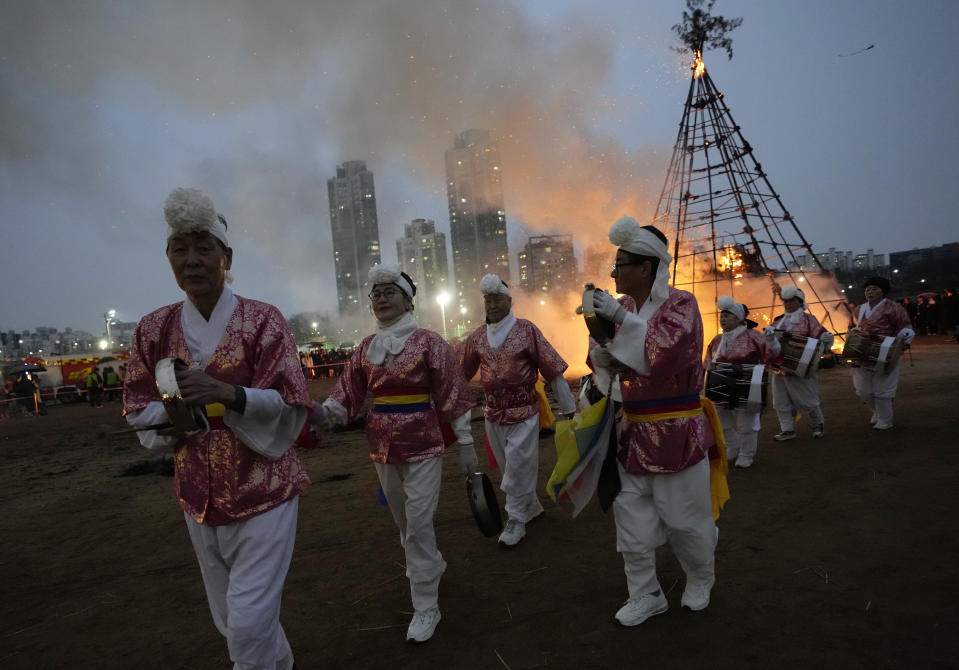 South Korean traditional band members perform near the burning Daljips, a wooden hut built on top of a hill, to celebrate the first full moon of the Lunar New Year in Seoul, South Korea, Saturday, Feb. 24, 2024. According to the lunar calendar, the first full moon falls on Feb. 24 this year. (AP Photo/Ahn Young-joon)