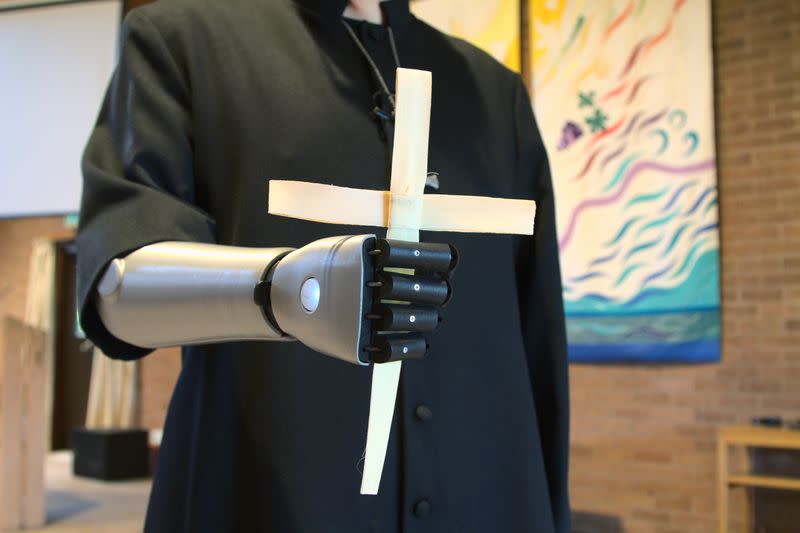 Priest-in-training Daniel Cant holds a cross as he demonstrates his bionic arm by British company Open Bionics at Christ Church in Colchester