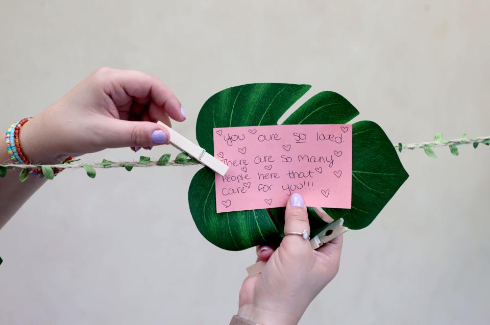 Becca Guenther, 30, of Garden City, a grief counselor at Angela Hospice Center, adds a quote of inspiration to the memorial walk during the second annual Camp Monarch run by Angela Hospice Center at the Madonna University Welcome Center in Livonia on Aug. 4, 2023. The two-day camp is for children ages 5 to 17 who have experienced the loss of a loved one to allow them to bond with other kids their age, talk about grief and get consoling from adults.