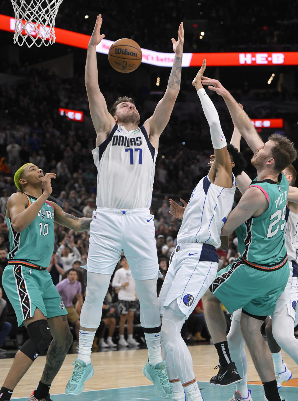 Dallas Mavericks' Luka Doncic (77) grabs for the rebound in the closing seconds of the team's NBA basketball game against the San Antonio Spurs, Saturday, Dec. 31, 2022, in San Antonio. Dallas won 126-125. (AP Photo/Darren Abate)