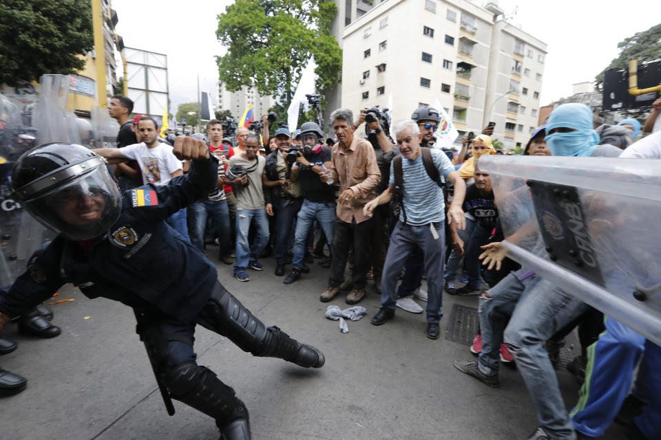 A police officer falls during clashes with supporters of opposition political leader Juan Guaido marching in Caracas, Venezuela, Tuesday, March 10, 2020. Guaido called for a march aimed at retaking the National Assembly legislative building, which opposition lawmakers have been blocked from entering. (AP Photo/Ariana Cubillos)