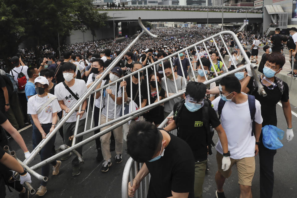 FILE - In this Wednesday, June 12, 2019, file photo, protesters carry barricades as they march toward the Legislative Council in Hong Kong. Hundreds of protesters surrounded government headquarters in Hong Kong on Wednesday as the administration prepared to open debate on a highly controversial extradition law that would allow accused people to be sent to China for trial. (AP Photo/Kin Cheung, File)