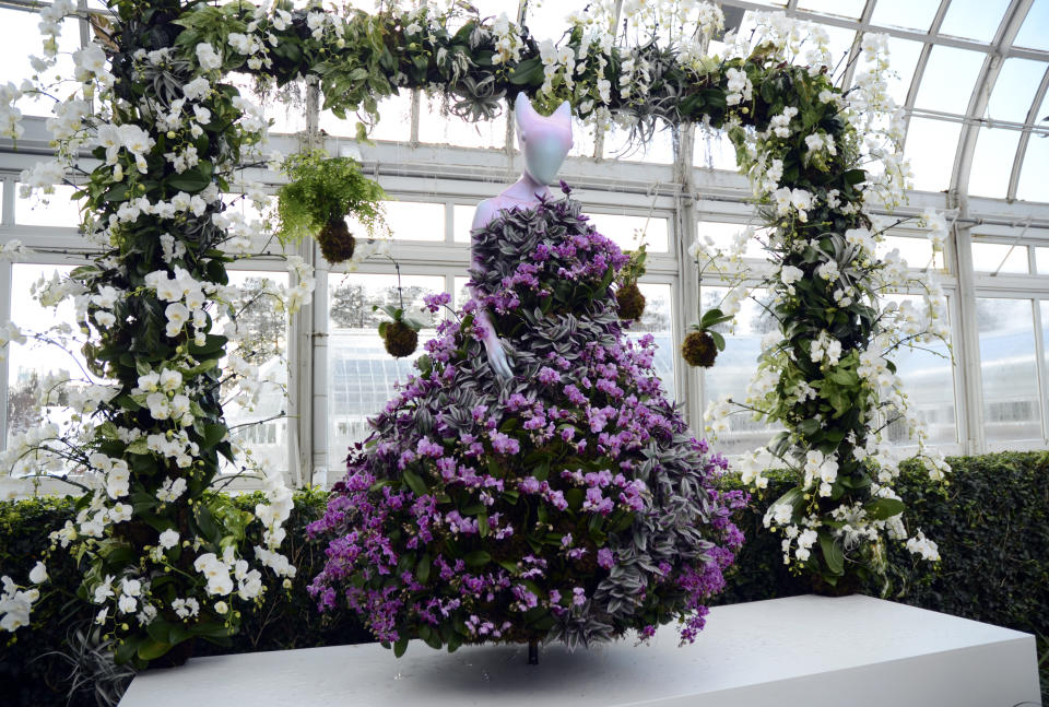 A fashion-creation inspired by nature of colorful miniature Phalaenopsis orchids from Collina Strada designed by Hillary Taymour in "The Orchid Show: Florals in Fashion" at The New York Botanical Garden, Saturday, Feb. 17, 2024, in the Bronx borough of New York. Orchid-decorated Kokedama floats above. (AP Photo/Pamela Hassell)