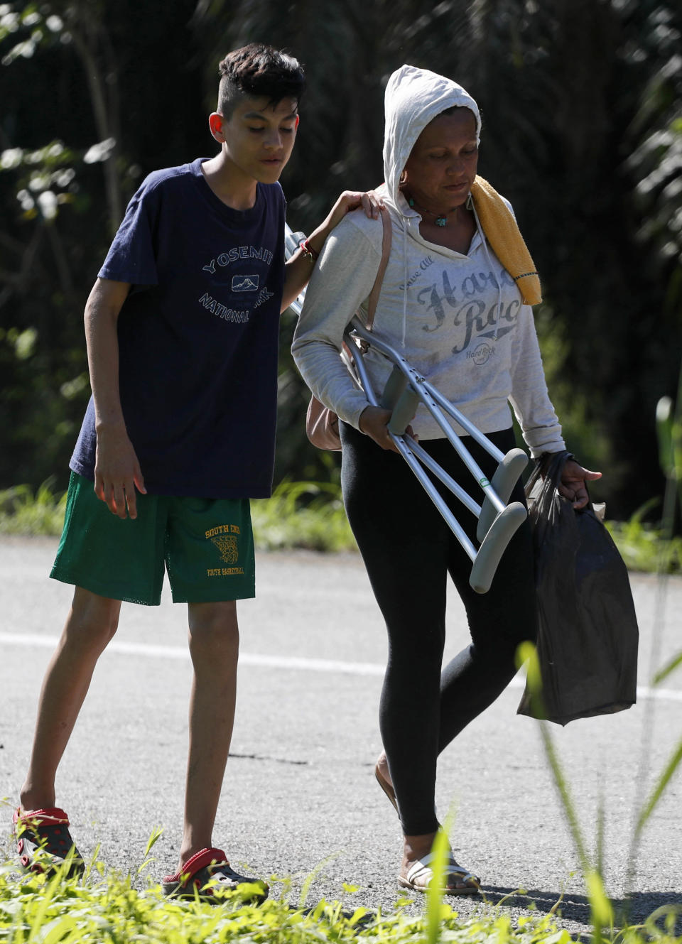 Nicaraguan migrant Axel leans on his mother Idania Molina Rocha, as they walk to Mapastepec, Mexico, Wednesday, Oct. 24, 2018, with a caravan that is making its way to the U.S. The 14-year-old was hit in the leg by what was perhaps police tear gas canister; he described it as a “bomb they shoot through a tube.” The wound is still visible on his femur, and he’s walked from Nicaragua through Honduras, El Salvador, Guatemala and now southern Mexico on crutches, still limping badly. (AP Photo/Moises Castillo)