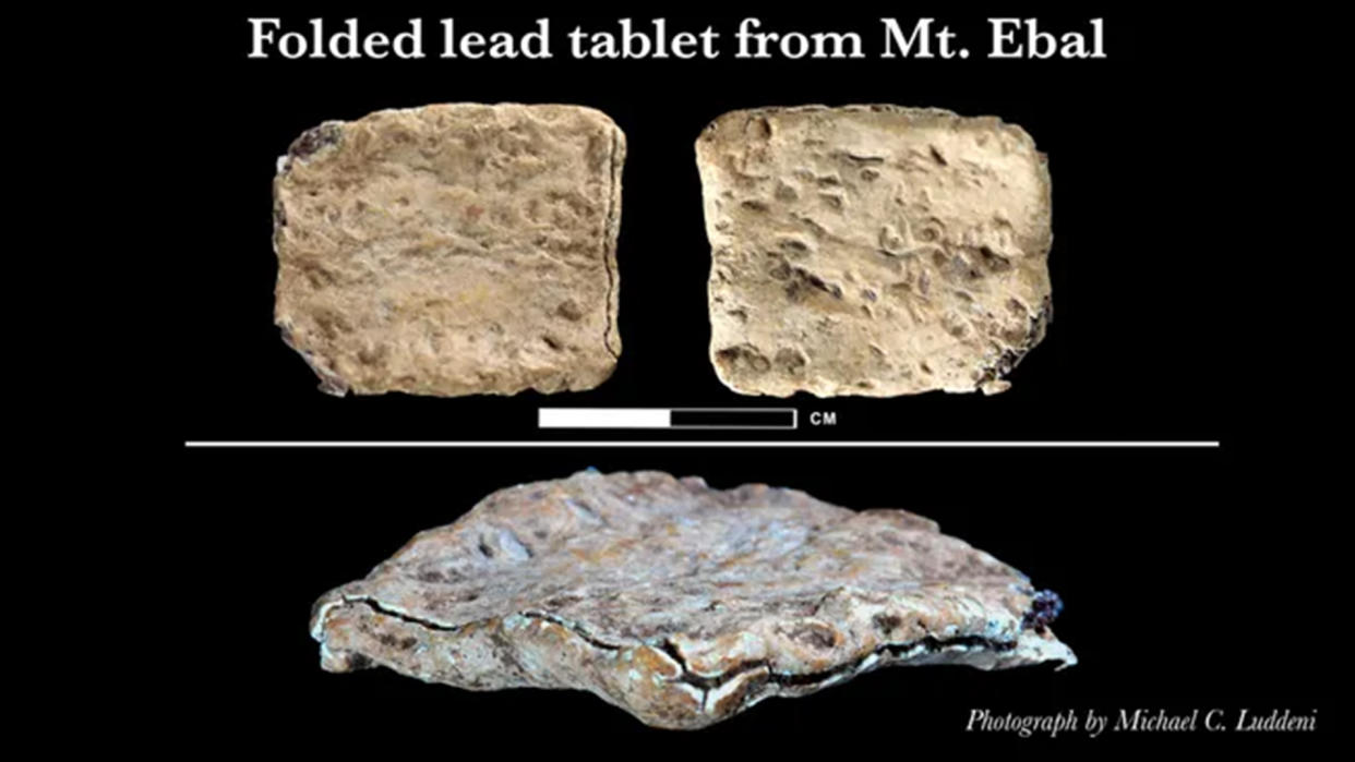  Photograph of curse tablet in light colored stone, in the shaped of a rough square. Photograph of the front, back and side. 