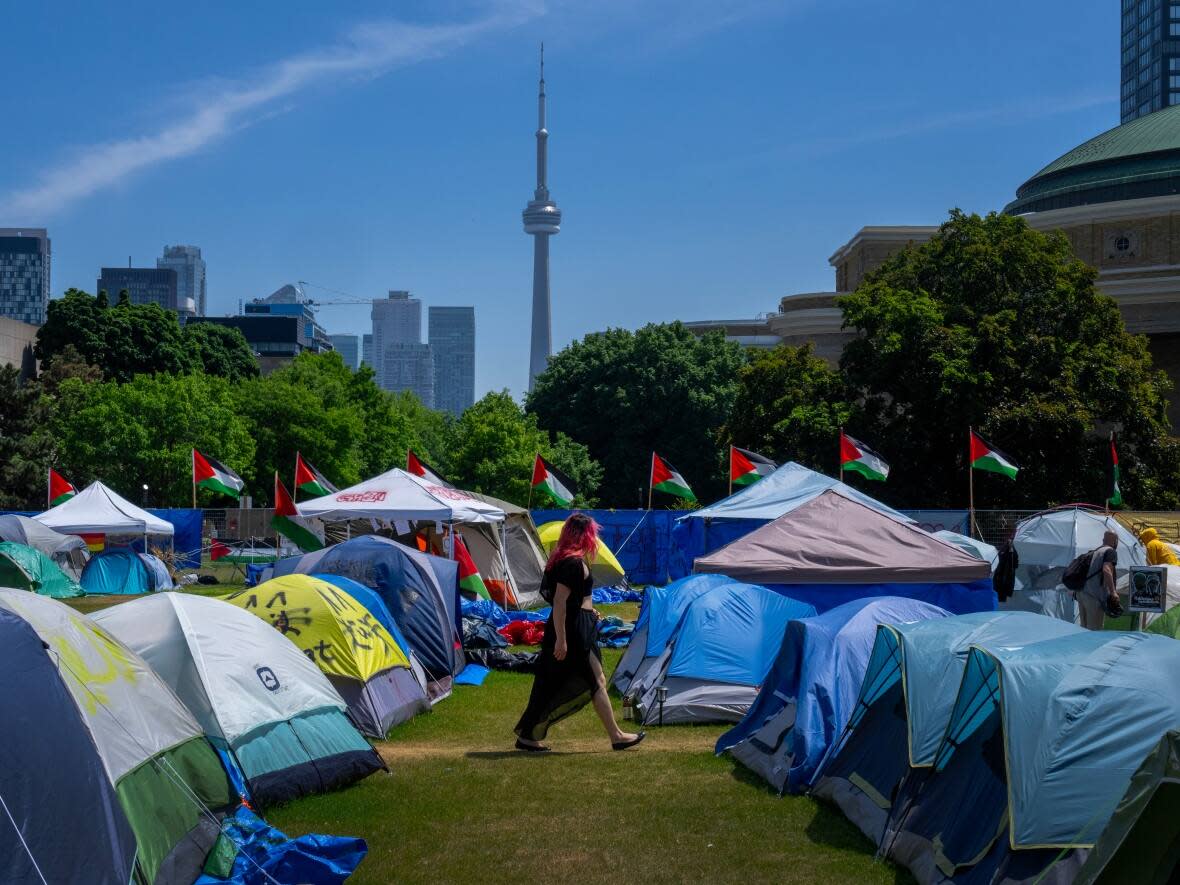 A woman walks between the tents in the pro-Palestinian encampment set up at the University of Toronto campus on May 26, 2024. (Frank Gunn/The Canadian Press - image credit)