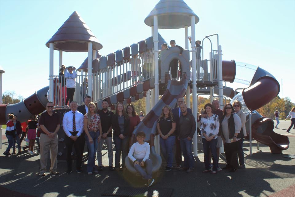 Eric Harshbarger and Dave Adams stand with donors in front of a newly opened playground on Wednesday.