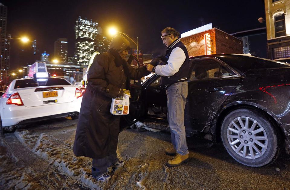 Doctor Angelo helps a homeless woman put on a pair of gloves that he gave her on the downtown streets in Chicago