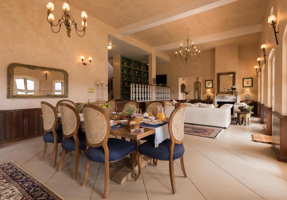 French windows and baroque chandeliers accentuate the double-height ceiling in the living cum dining area; while wooden wall panels lend a cosy touch to the space.