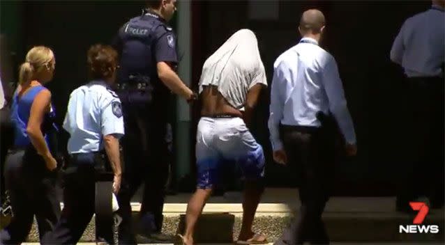 The alleged serial rapist (white shirt pulled up) remains in police custody. Source: 7 News