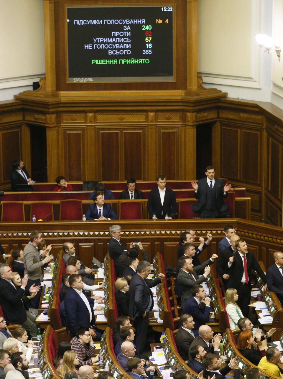 Lawmakers of president Volodymyr Zelenskiy's party 'Servant of the People' clap hands, Ukraine's Prime Minister Oleksiy Honcharuk and Minister of Economic Development Tymofiy Mylovanov in the background, after the land sale bill vote during a session of the parliament in Kyiv, Ukraine, Wednesday, Nov. 13, 2019. After an hours-long debate in parliament in which tempers flared, the majority of Ukrainian lawmakers passed a bill lifting the ban on buying and selling farmland. It received 240 votes, requiring 226 to pass. (AP Photo/Efrem Lukatsky)