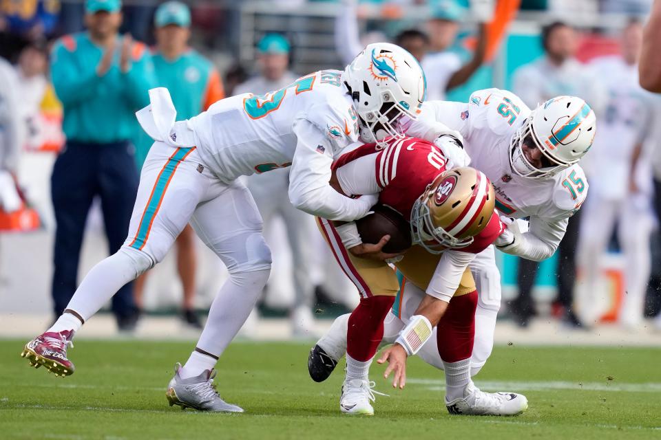 San Francisco 49ers quarterback Jimmy Garoppolo, middle, is sacked by Miami Dolphins linebacker Jerome Baker, left, and linebacker Jaelan Phillips (15) during the first half.