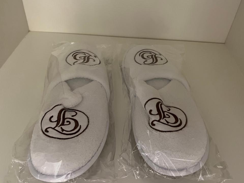 two pairs of white grand floridian slippers in plastic wrappings in a closet inside a room at the grand floridian resort