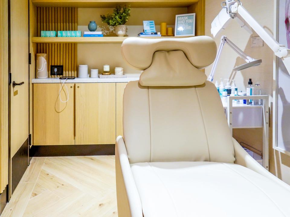 Inside a facial treatment room with wood floors and cabinets and a leather beige chair.