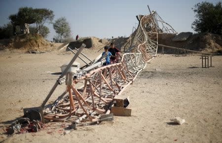 Palestinian boys walk next to a destroyed communication structure at a training camp belonging to the Islamist group Hamas after it was hit by an Israeli air strike in the northern Gaza Strip September 19, 2015. REUTERS/Mohammed Salem