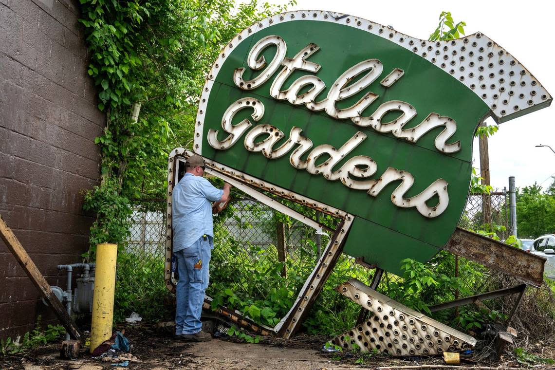 Jacob Rock removes a part the Italian Gardens neon sign. The sign will go into storage until it can be renovated.