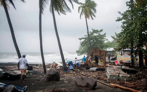People walk among debris at a restaurant  - Credit: LIONEL CHAMOISEAU/AFP