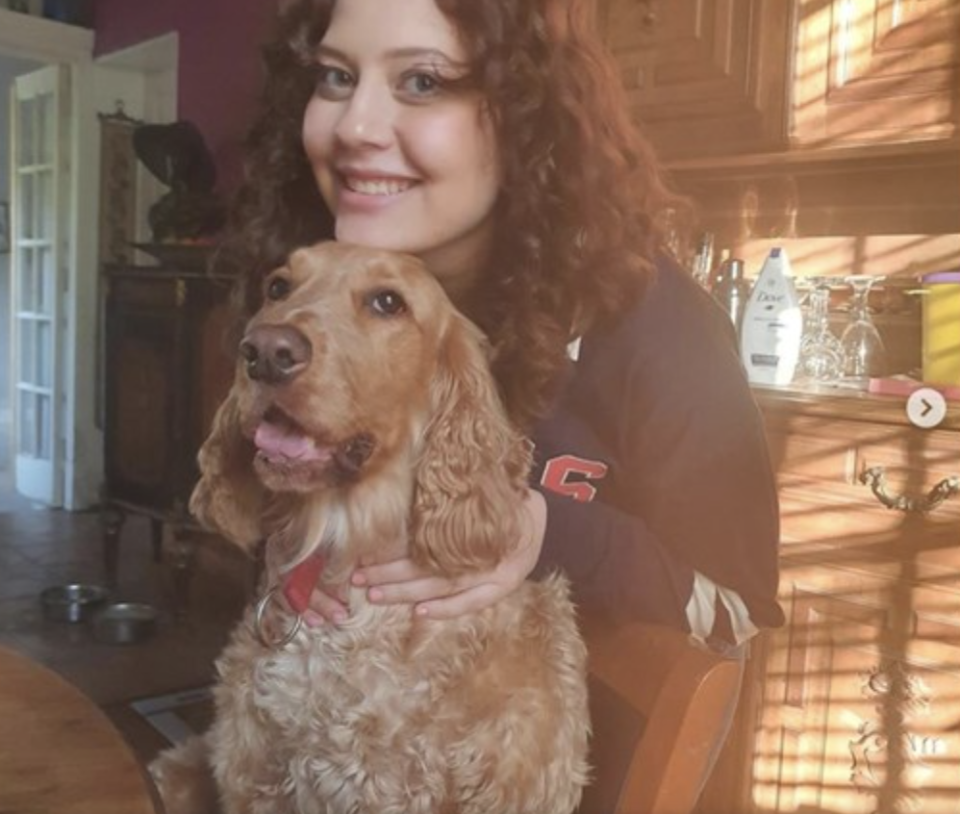 Simone Norowzian smiles while holding a dog. 