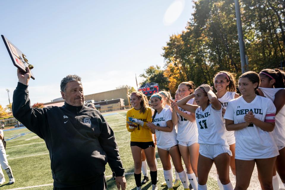 DePaul plays Wayne Valley in a girls soccer match at Passaic Tech in Wayne, NJ on Saturday October 22, 2022. DePaul coach Steven Beneventine holds up a trophy as the team celebrates a 2-0 win over Wayne Valley. 