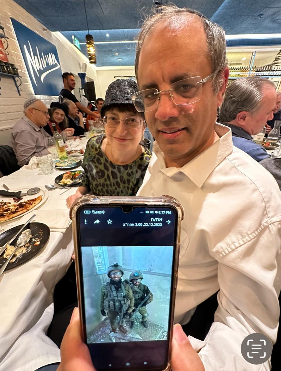 Akiva Sylvetsky and his wife, Noa, show a photo of their son Evyatar, now deployed in Gaza.