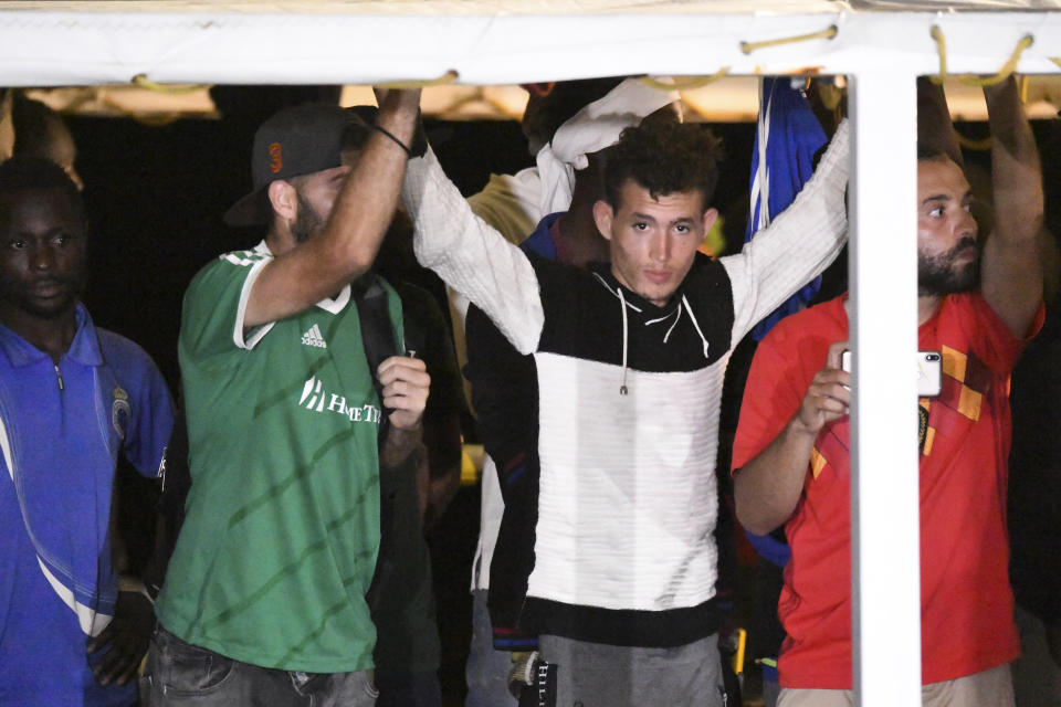 Migrants on the Open Arms rescue ship prepare to disembark on the Sicilian island of Lampedusa, southern Italy, Tuesday, Aug. 20, 2019. Italian prosecutor Luigi Patronaggio has ordered the seizure of a migrant rescue ship and the immediate evacuation of more than 80 migrants remaining on board, capping dramatic developments that saw 15 migrants jump into the sea in a desperate bid to reach land and the Spanish government dispatch a Naval ship on a long journey to resolve the escalating crisis. (AP Photo/Salvatore Cavalli)