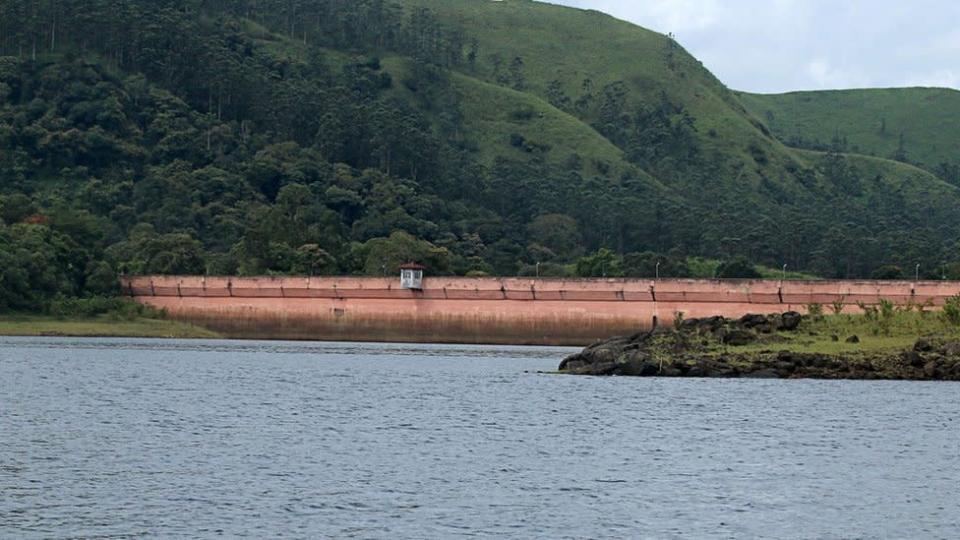 File photo showing the Mullaiperiyar Dam extending from the lake to a green hillside with trees