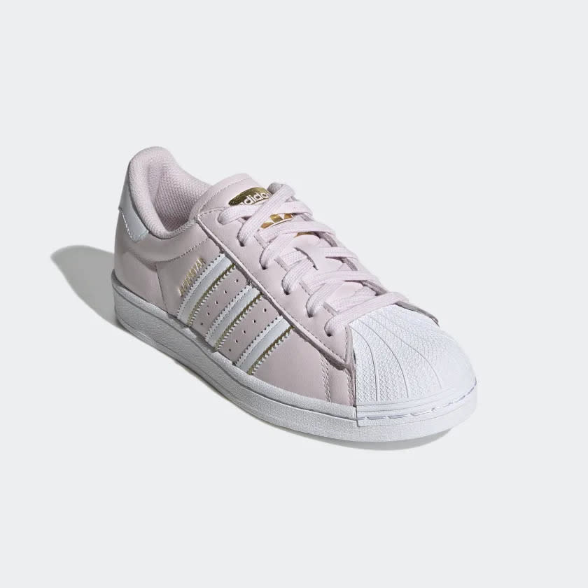 Pink shoes with gold trim and three white stripes.