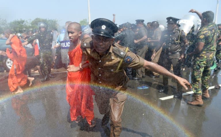 A Sri Lankan police personnel leads a monk from a protest in the southern port city of Hambantota on January 7, 2017