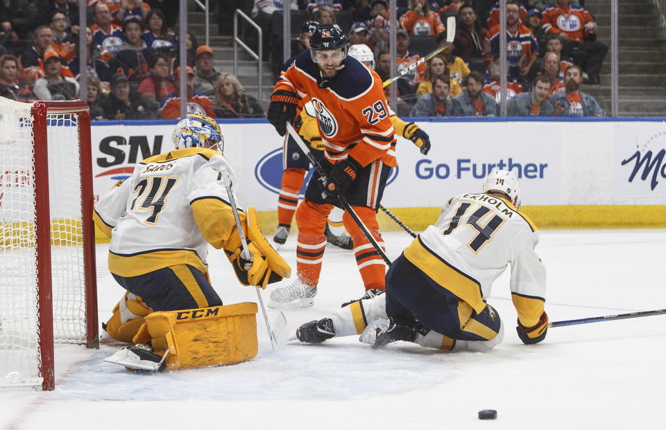 Nashville Predators goalie Juuse Saros (74) makes the save against Edmonton Oilers' Leon Draisaitl (29) as Mattias Ekholm (14) defends during second-period NHL hockey game action in Edmonton, Alberta, Saturday, Feb. 8, 2020. (Jason Franson/The Canadian Press via AP)