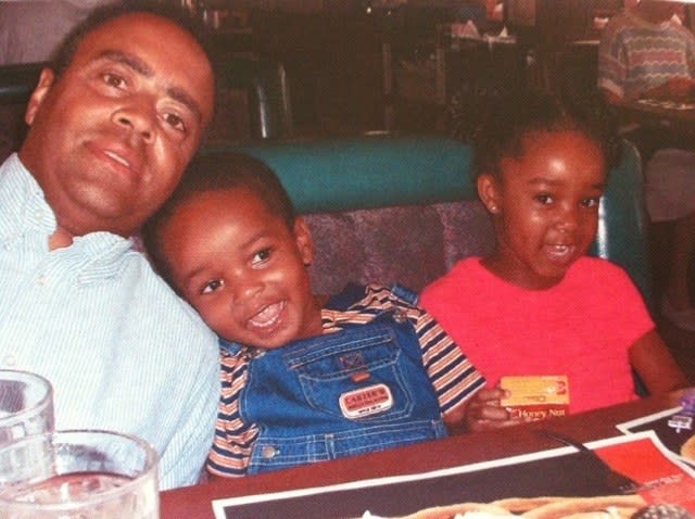 Uncle Blakey, Gabrielle's brother, and Gabrielle sitting in a booth at a restaurant. Her brother has his head rested on Uncle Blakey's shoulder.