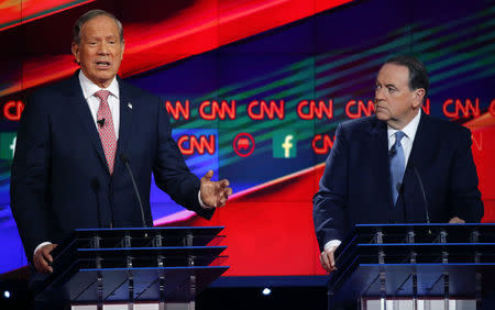 Mike Huckabee listens as George Pataki delivers his opening statement. REUTERS/Mike Blake