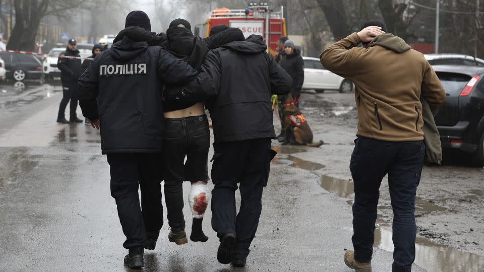 An injured man is helped away from the scene of the strike, which killed at least 14 people. - Victor Sajenko/AP