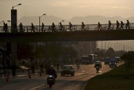 FILE - Commuters walk their bicycles across a pedestrian bridge and ride on a bike path next to the street in Bogota, Colombia, Tuesday, March 17, 2020. By some measures, over 9% of trips in the capital are by bicycle, putting it in the top tier globally and a model that other cities in Latin America are trying to emulate. (AP Photo/Fernando Vergara, File)