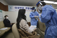 A medical staff, right, checks a nursing home worker after receiving the first dose of the AstraZeneca COVID-19 vaccine at a health care center in Seoul Friday, Feb. 26, 2021. South Korea on Friday administered its first available shots of coronavirus vaccines to people at long-term care facilities, launching a mass immunization campaign that health authorities hope will restore some level of normalcy by the end of the year. (Jung Yeon-je /Pool Photo via AP)