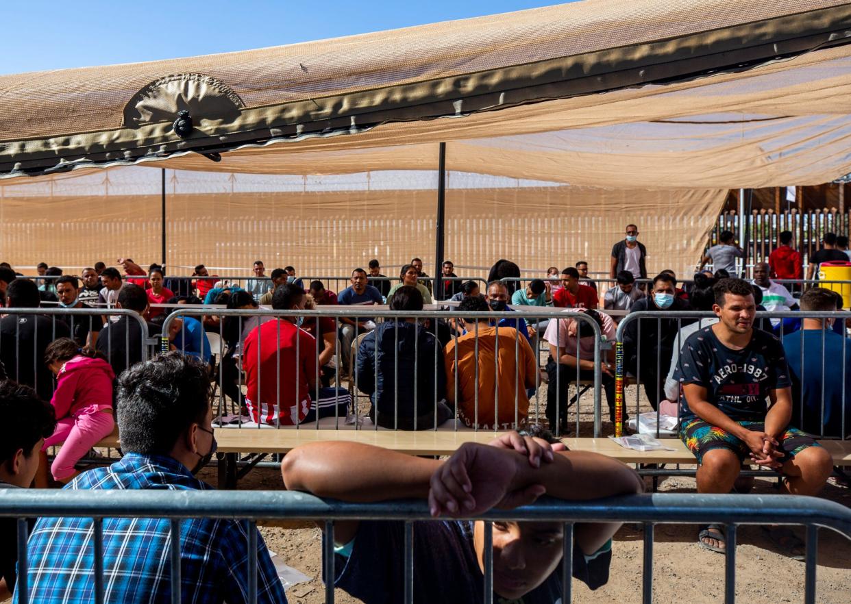 Migrants sit in an area as they are processed by Customs and Border Protection after having crossed the Rio Grande river from Ciudad Juarez, Mexico to El Paso, Texas, seeking asylum on Tuesday.