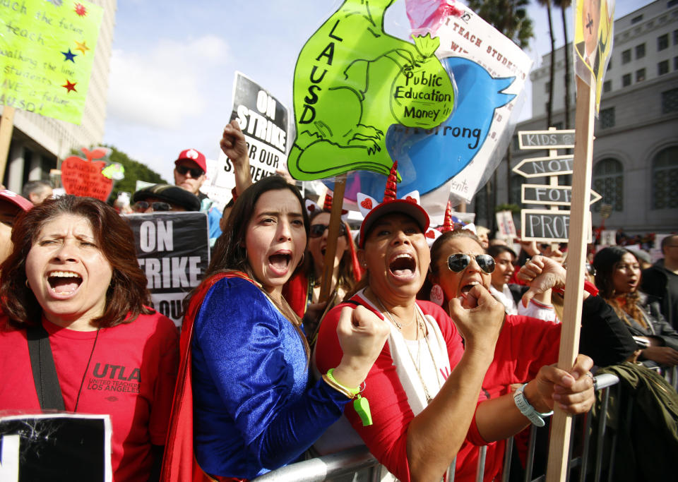 FILE - In this Friday, Jan. 18, 2019 file photo, elementary school teachers Iris Marin, center, and Mireya Gutierrez, right, and Lorena Redford, clench fists at a rally in downtown Los Angeles. Los Angeles teachers who declared a victory after a six-day strike have added momentum to a wave of activism by educators. They've tapped a common theme and found success by framing their cause as a push to improve public education, not just get pay raises. (AP Photo/Damian Dovarganes, File)