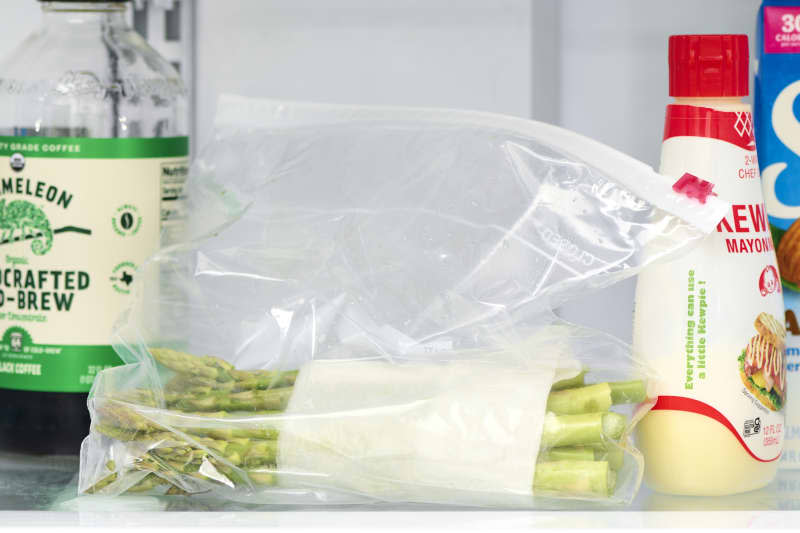 head on shot of asparagus in a ziploc bag in the fridge