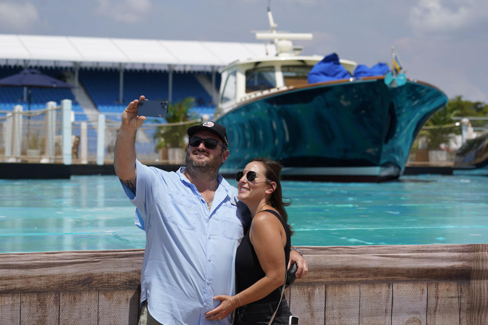 Race fans pose for a selfie at the man-made marina and beach club during the Formula One Miami Grand Prix auto race at Miami International Autodrome, Friday, May 6, 2022, in Miami Gardens, Fla. (AP Photo/Darron Cummings)