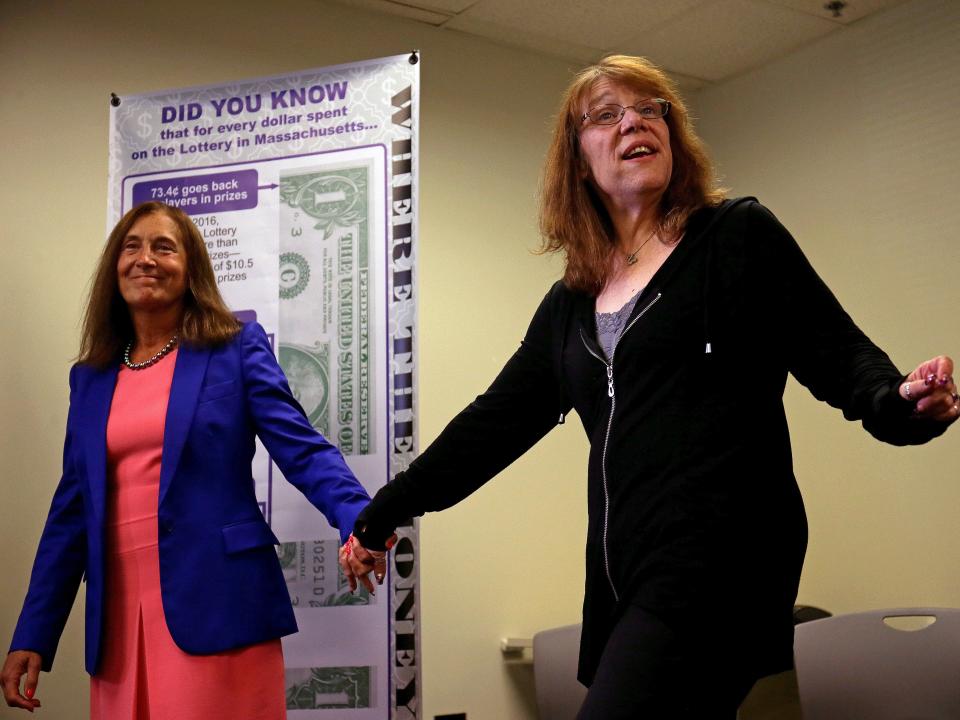 Massachusetts State Treasurer Deborah Goldberg, left, holds the hand of the winner of the $758.7 million Powerball jackpot Mavis L. Wanczyk, right, in Braintree, Massachusetts.