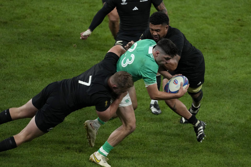 Ireland's Jimmy O'Brien, centre, is tackled by New Zealand's Ardie Savea, right, and his teammate Sam Cane during the Rugby World Cup quarterfinal match between Ireland and New Zealand at the Stade de France in Saint-Denis, near Paris Saturday, Oct. 14, 2023. (AP Photo/Themba Hadebe)